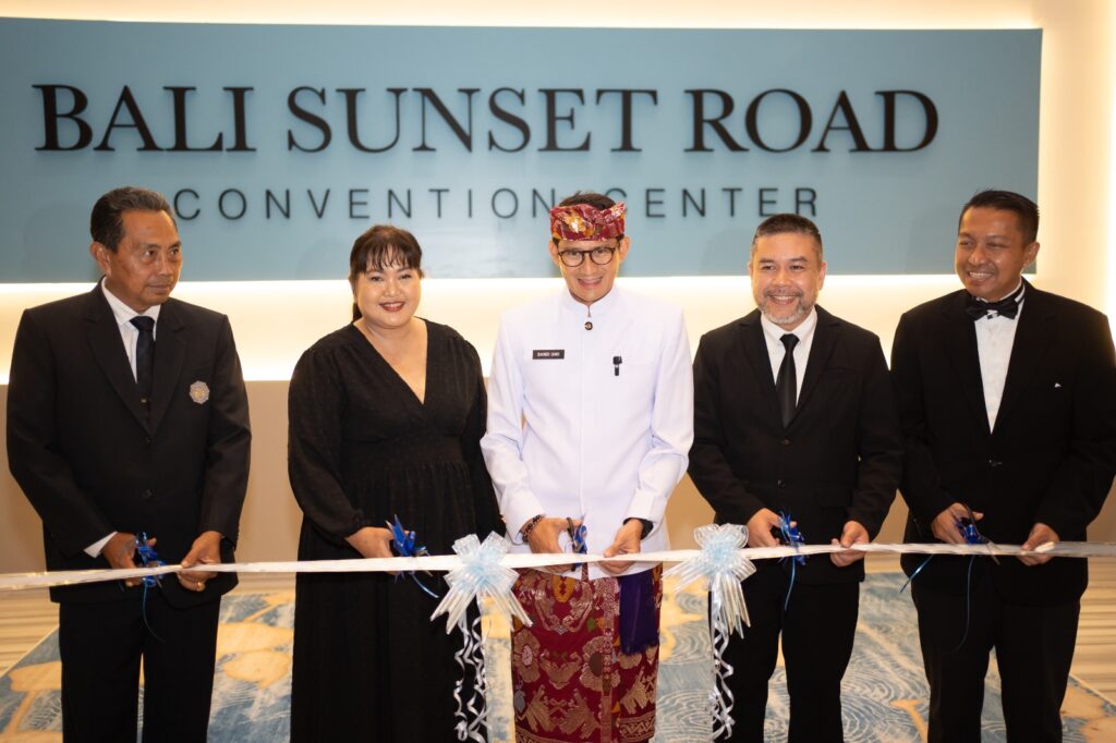 A group of five people, including one in traditional attire, participate in a ribbon-cutting ceremony at the elegant Bali Sunset Road Convention Center.